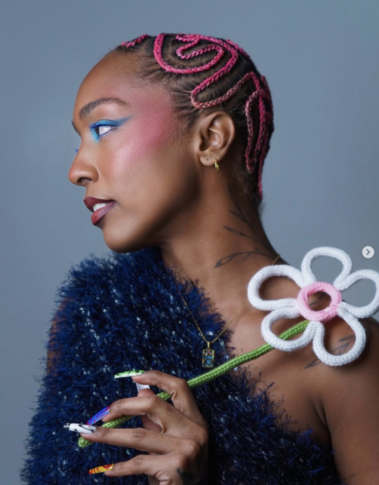 Portrait in blue tinsel holding a single crocheted flower