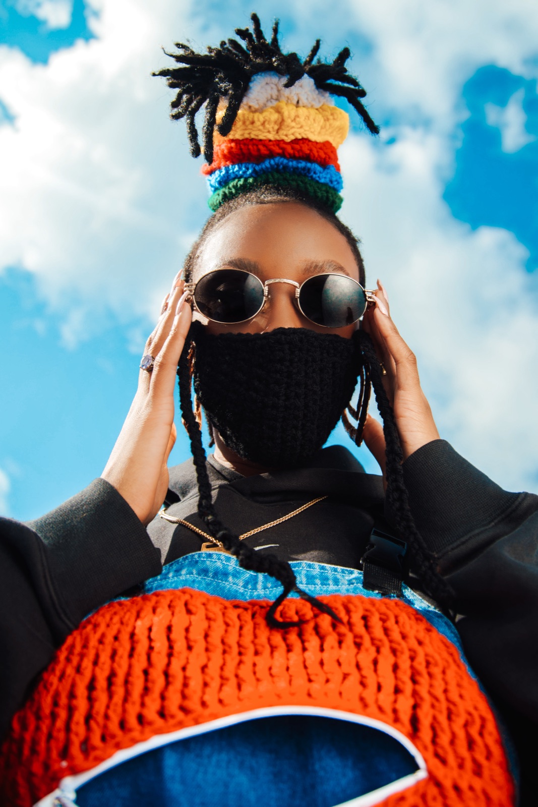 Portrait in a crocheted mask and stacked yarn crown against open sky