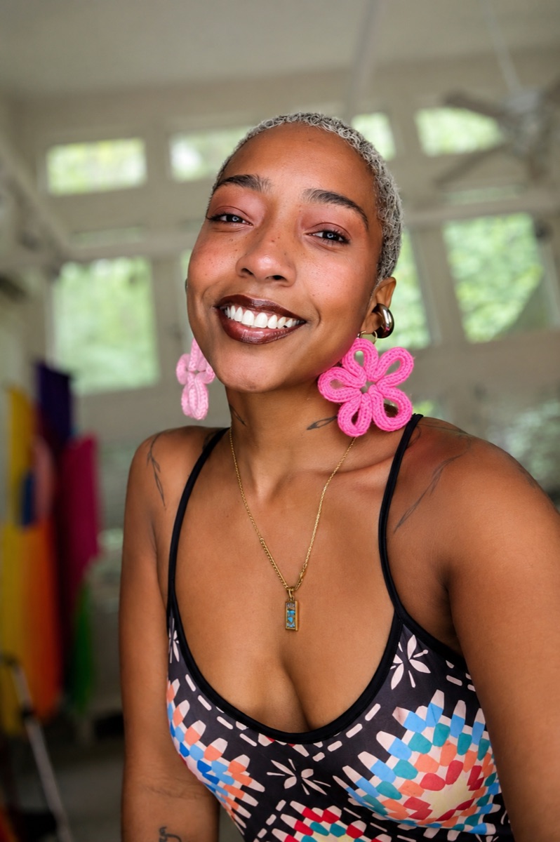 Woman smiling wearing pink knit flower earrings