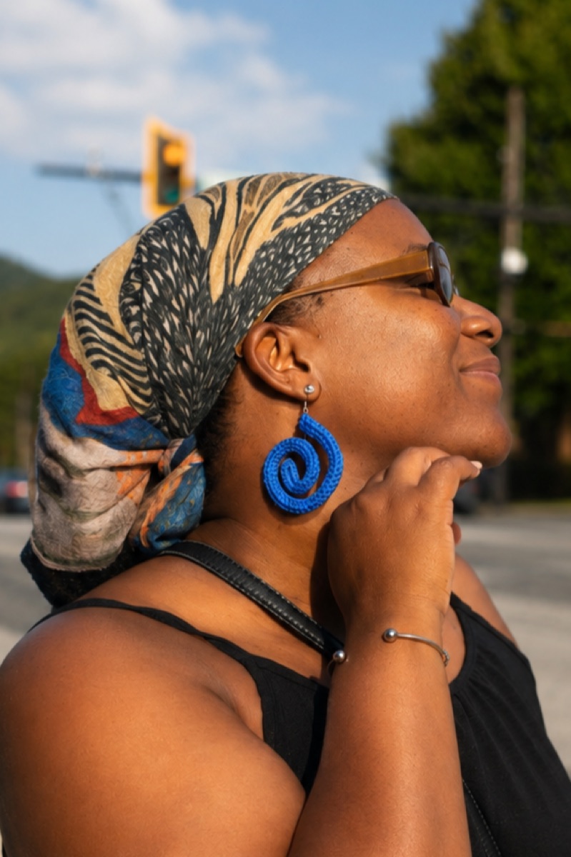 Woman in headscarf and sunglasses wearing a blue knit spiral earring